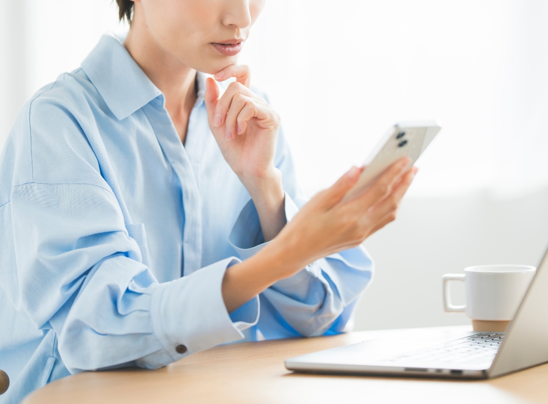 スマートフォンを見ながら仕事をする女性
